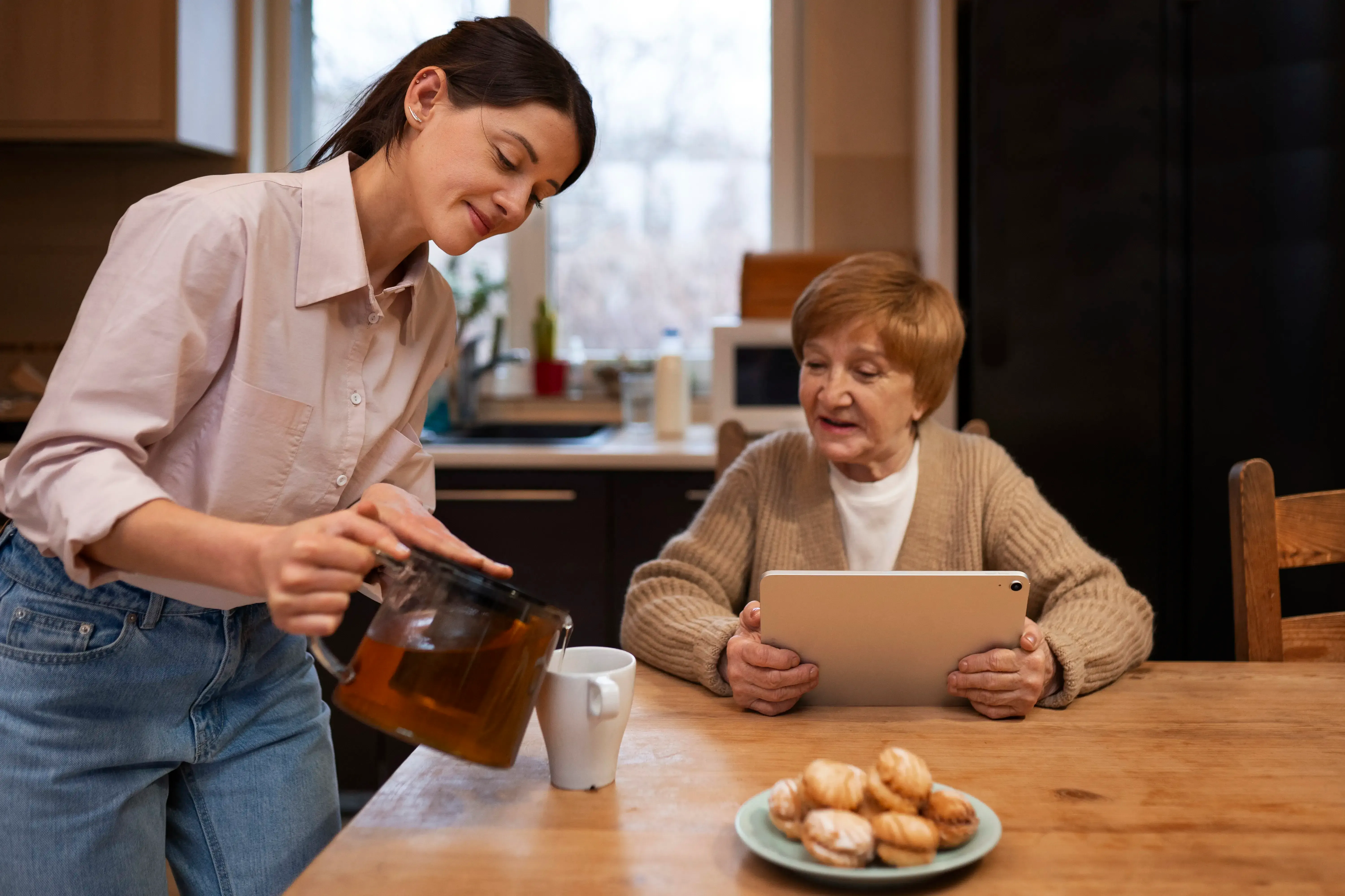 A care professional sharing a cup of tea with an elderly client.